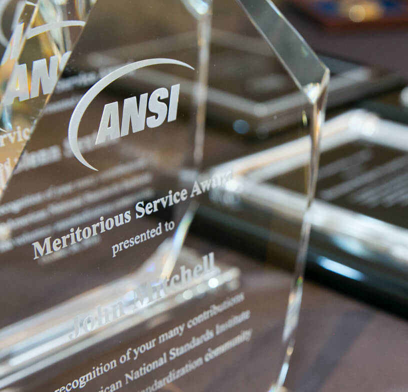 A close-up of a crystal award and plaque presented to ANSI Leadership and Service Award winners.