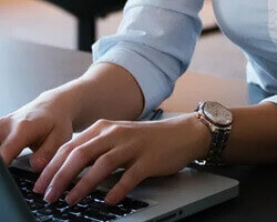 A woman's hands typing on a keyboard. 