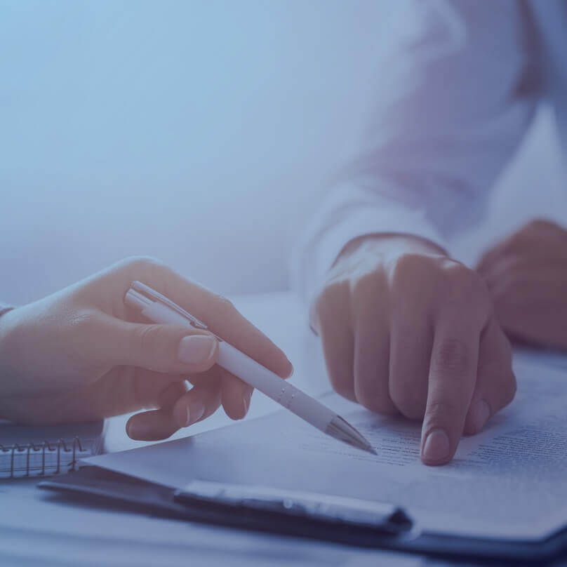 Two people's hands with a pen and a document being reviewed. 