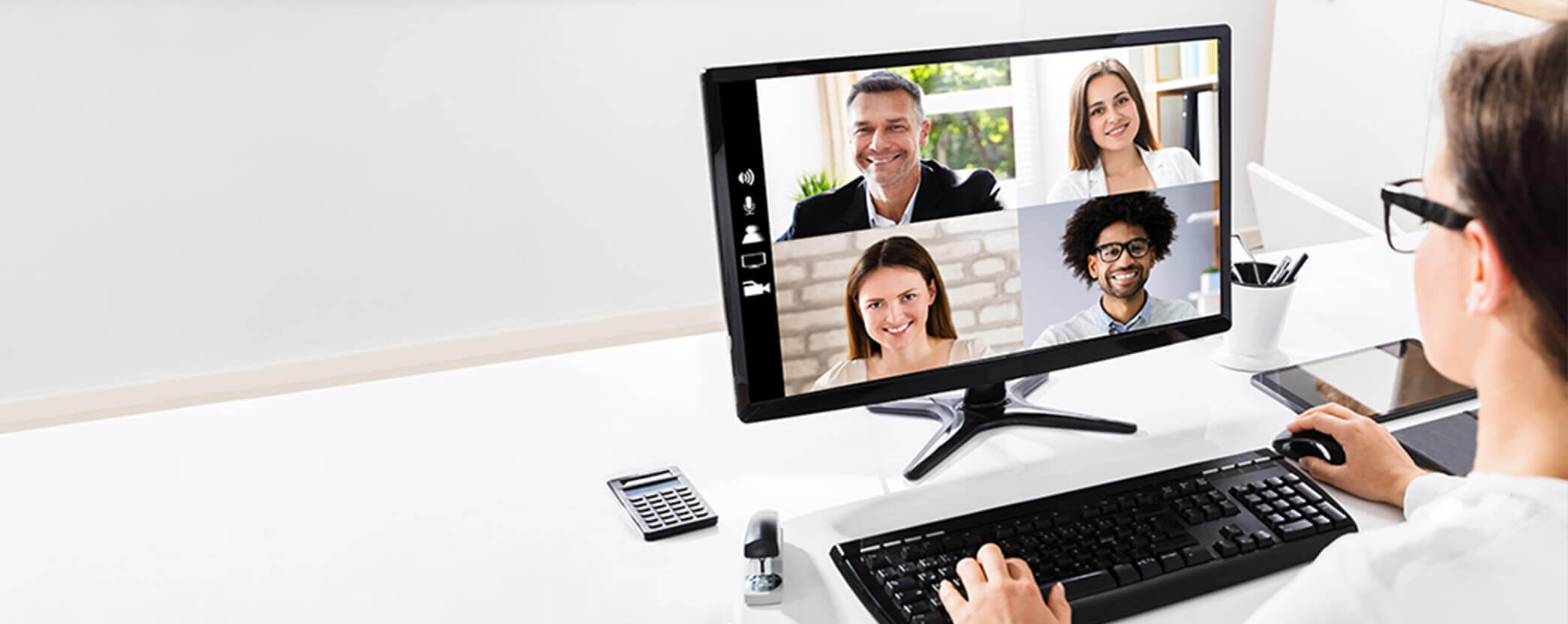 A woman at a desk particpating in a virtual meeting on her computer. 