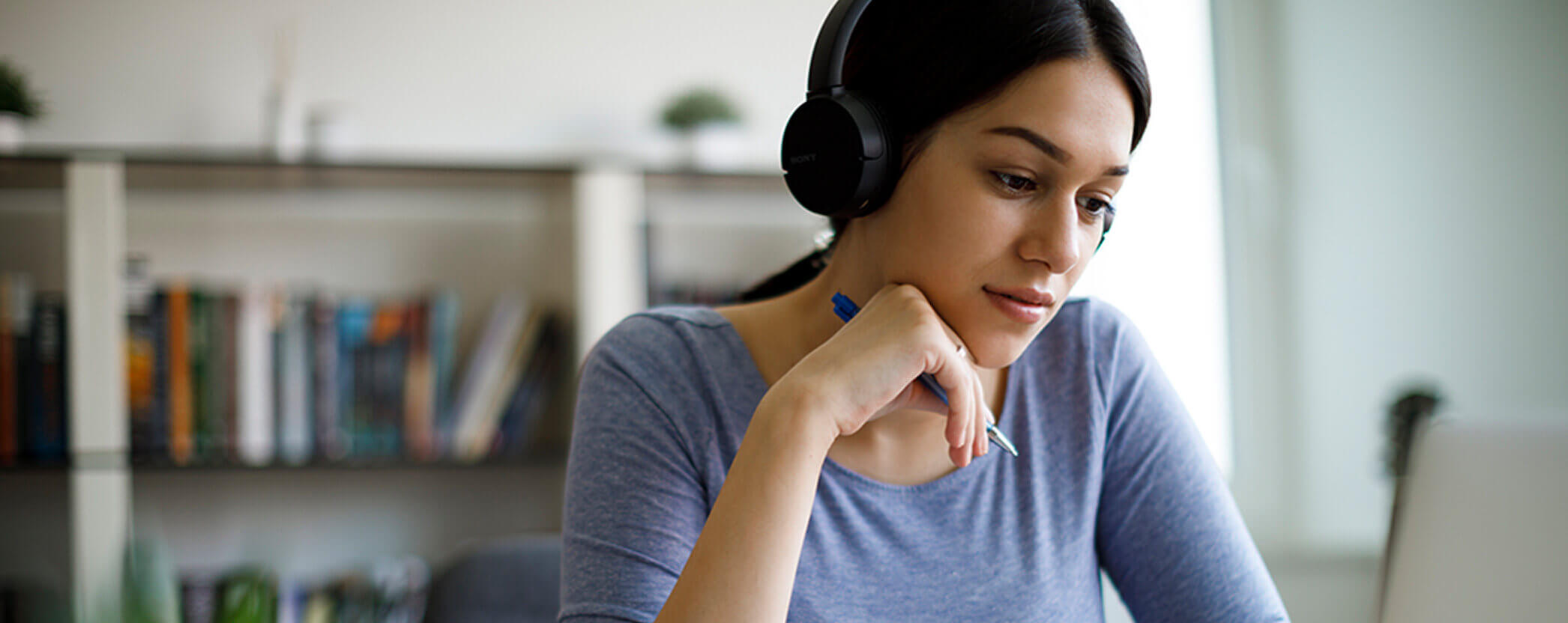 A student sits at her laptop with headphones for remote learning.
